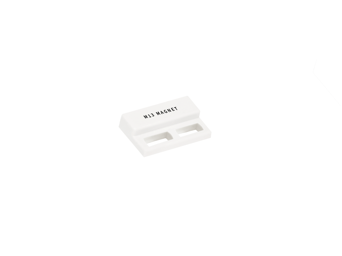 A small rectangular white plastic component labeled MJ1 MAGNET from the M13 Series Magnet line, featuring two rectangular slots on the bottom and isolated on a plain white background. by Standex Detect