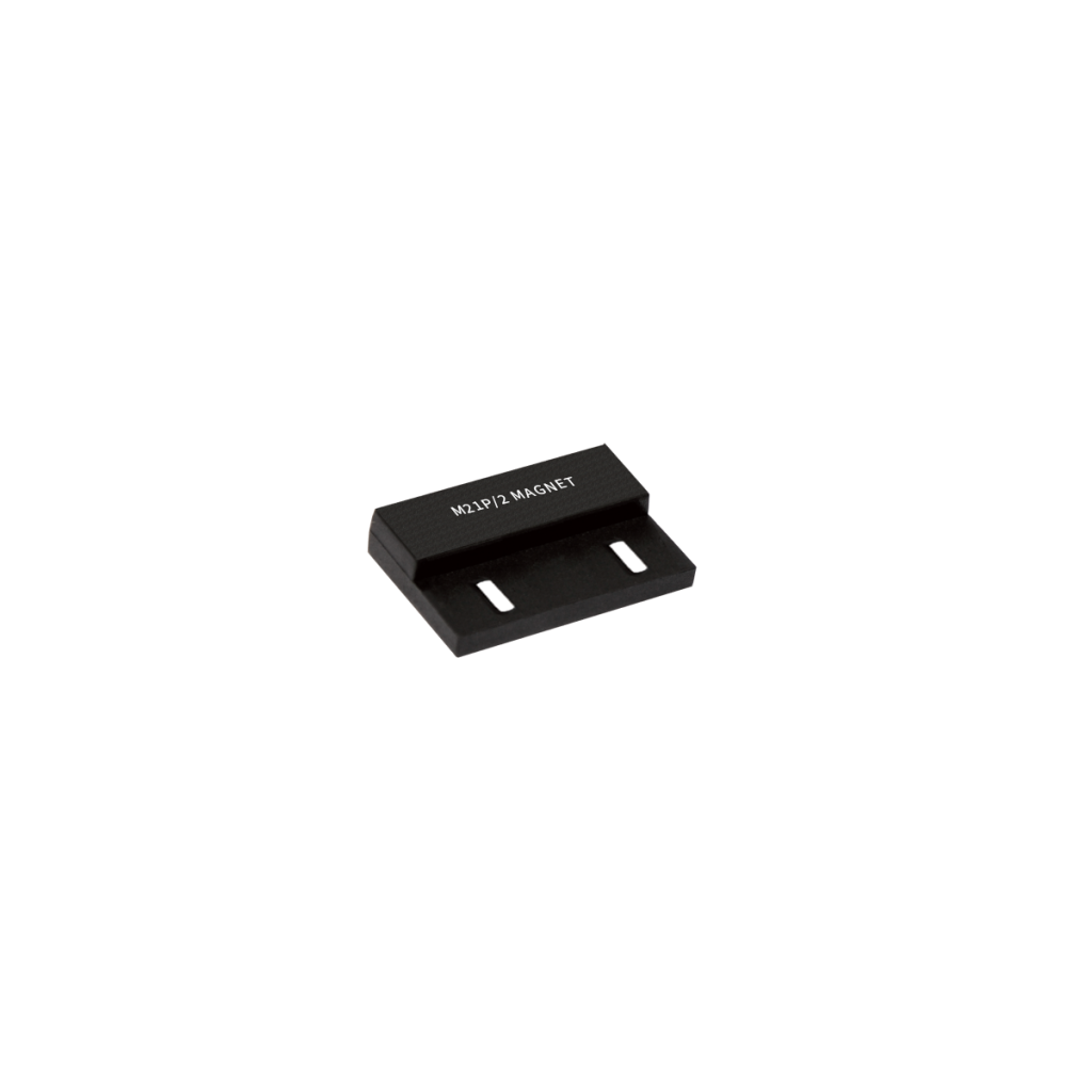 A small, rectangular black magnetic mounting bracket with two slots and the text R12/13 MAGNET printed on top, displayed on a white background. by Standex Detect