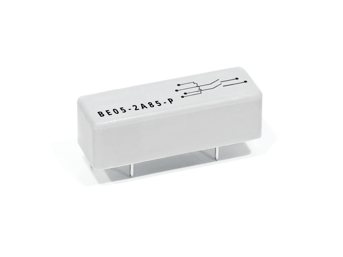 A small, rectangular, white BE Series Reed Relay featuring four metal pins on the bottom, a black circuit diagram, and the label BE05-2A85-P printed on the top surface. by Standex Detect